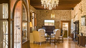 Une pièce spacieuse avec une grande porte en bois, un lustre, une cheminée et un téléviseur.