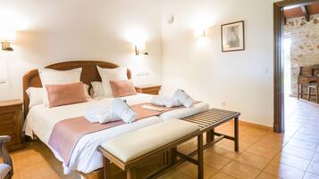 Una habitación de hotel con una cama grande, un banco y un escritorio.