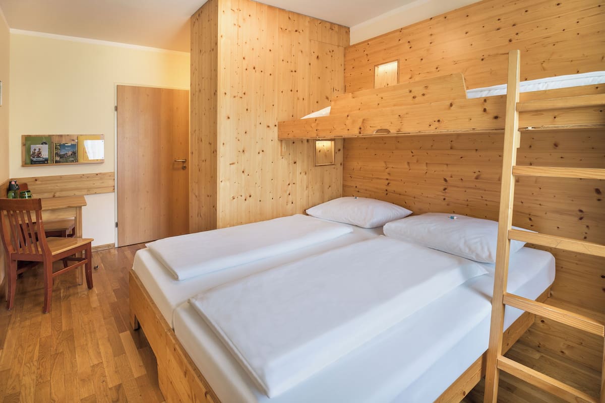 Een kamer met twee bedden, een houten bureau en een stoel.