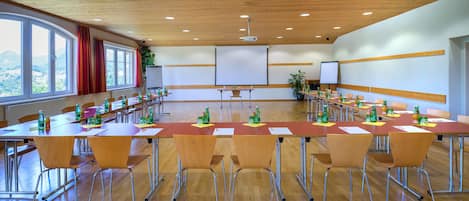 A conference room with wooden floors, long tables, and chairs.