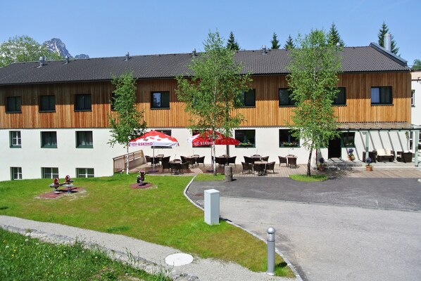 A hotel with outdoor seating, a covered patio, and a view of a mountain. - JUFA Hotel Bad Aussee (Bad Aussee)