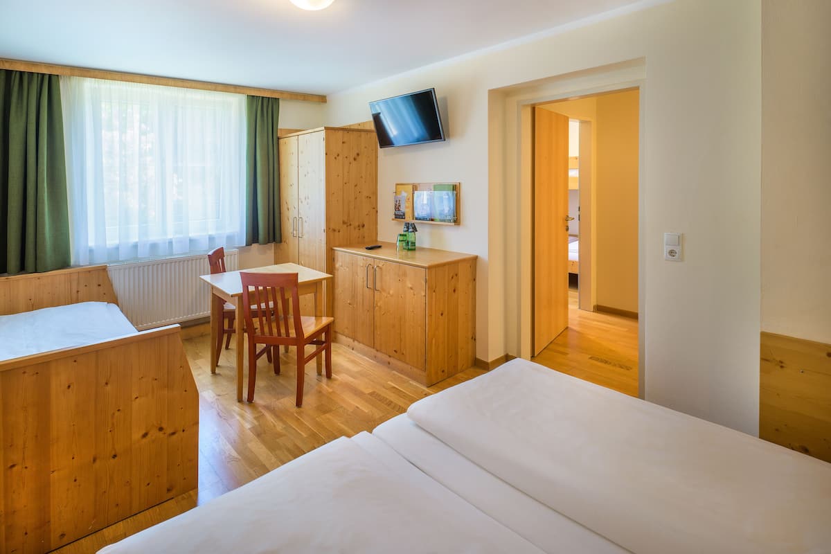 Een hotelkamer met een bed, een bureau, een stoel, een televisie en een raam met gordijnen.