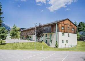 A modern building with a flat roof, large windows, and a green entrance.