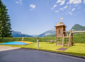 Una estructura de madera con un mirador, una piscina pequeña y vistas a las montañas.