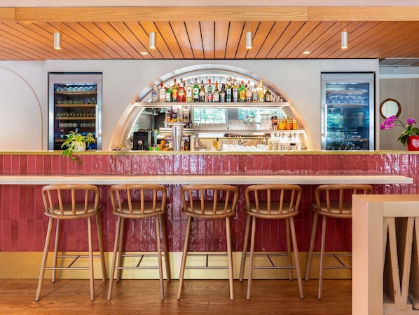A bar area with a curved counter, stools, and a variety of bottles and glasses.