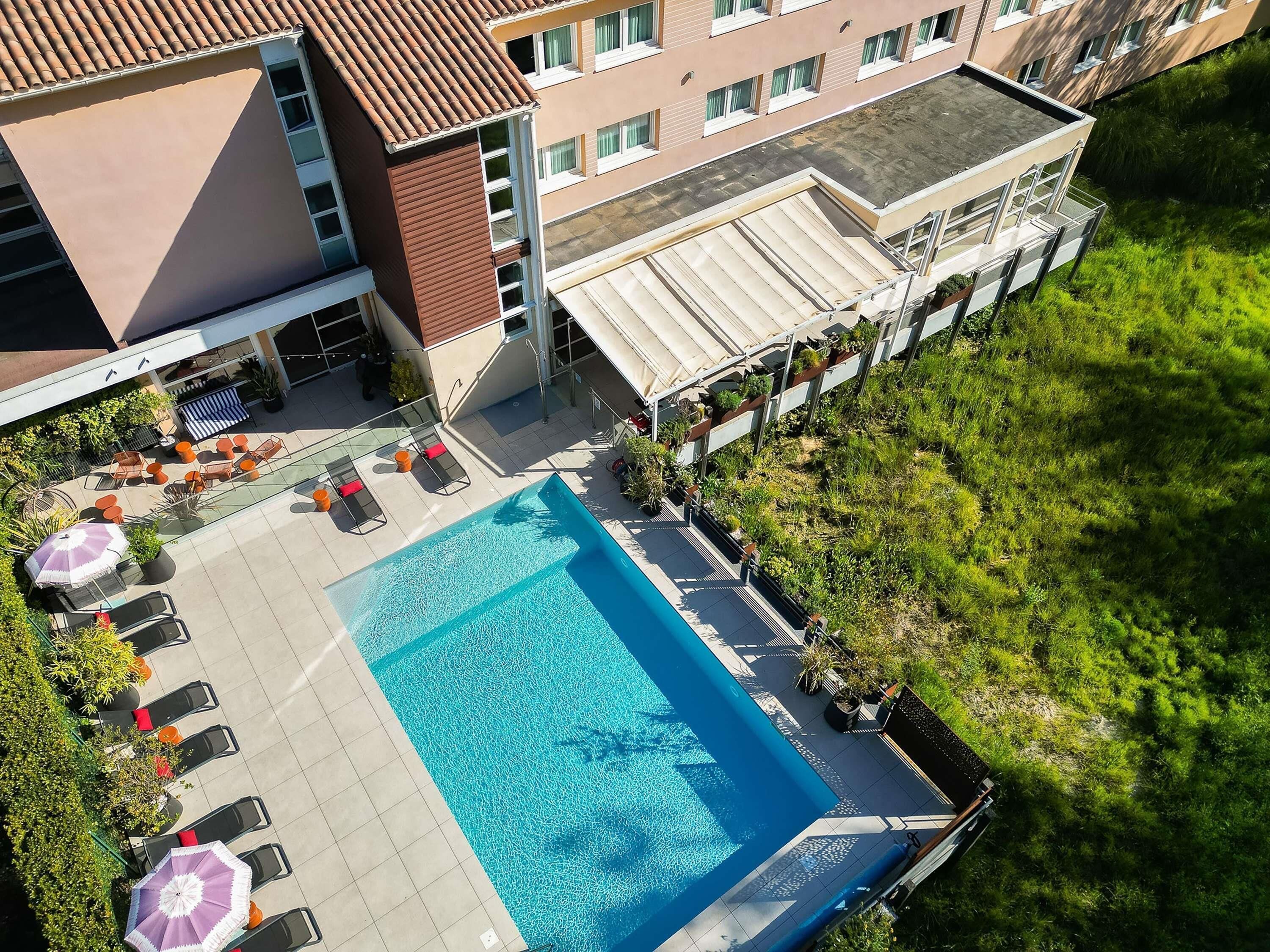 Vista aérea de un hotel con piscina, mobiliario exterior y jardín.