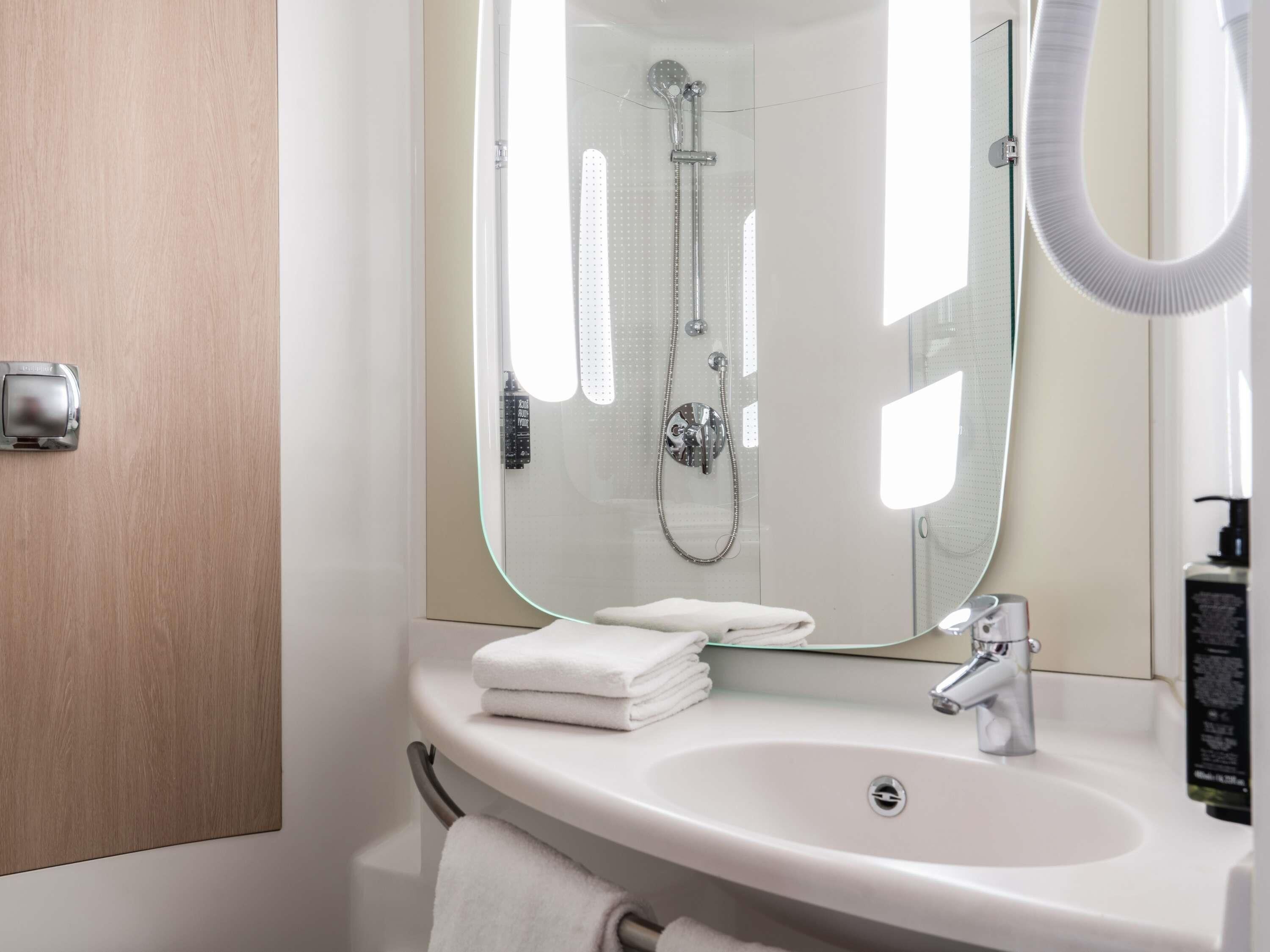 A bathroom with a sink, mirror, and shower.