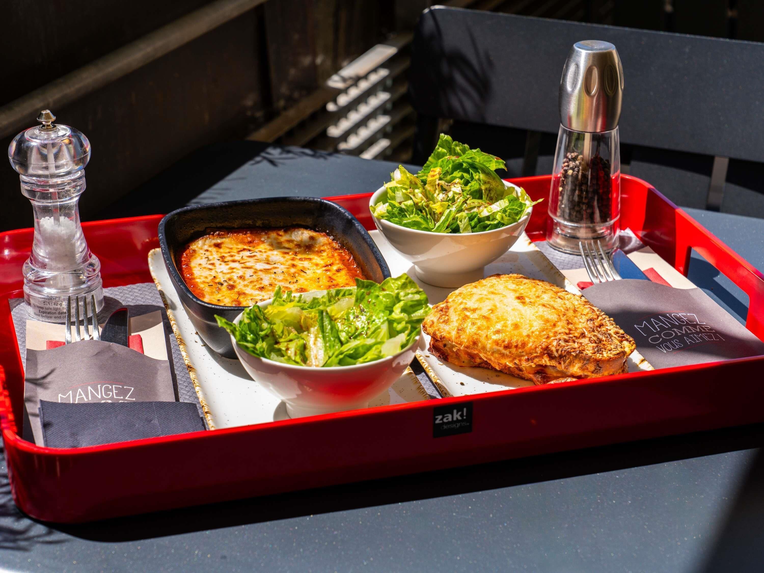 A tray with a baked dish, salad, and a beverage container.