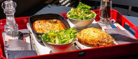 A tray with a baked dish, salad, and a beverage container.