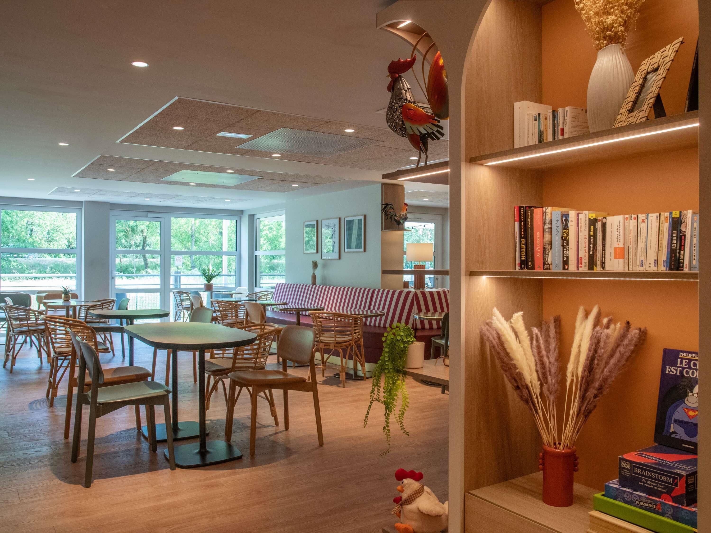 A modern interior with wooden furniture, a bookshelf, and a view of greenery outside.