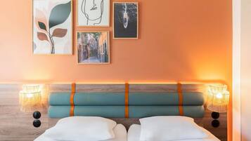 Una habitación de hotel con una cama, dos lámparas de noche y tres cuadros en la pared.