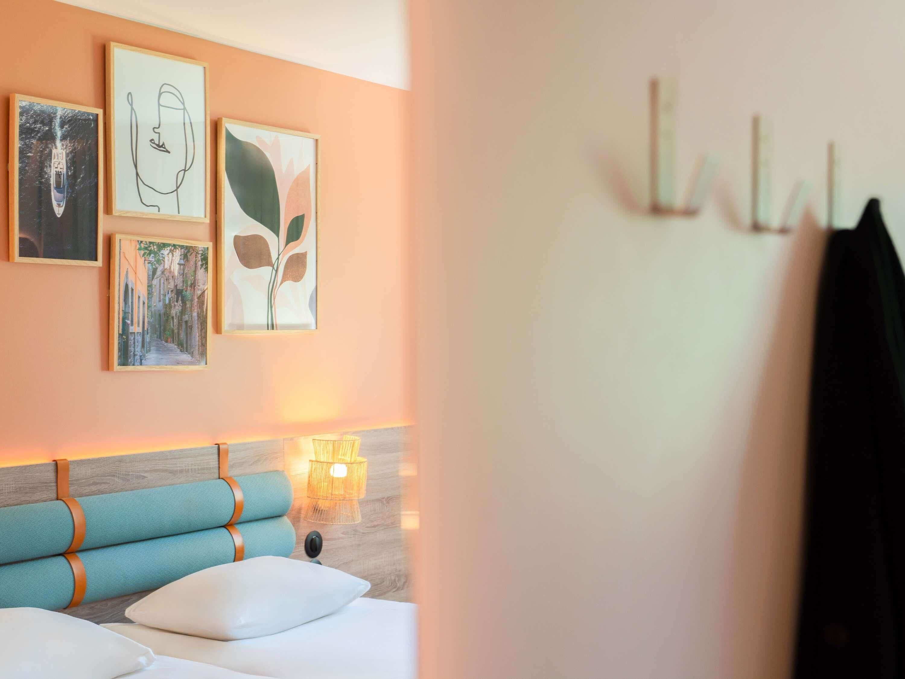 A hotel room with a bed, a headboard, and wall art.