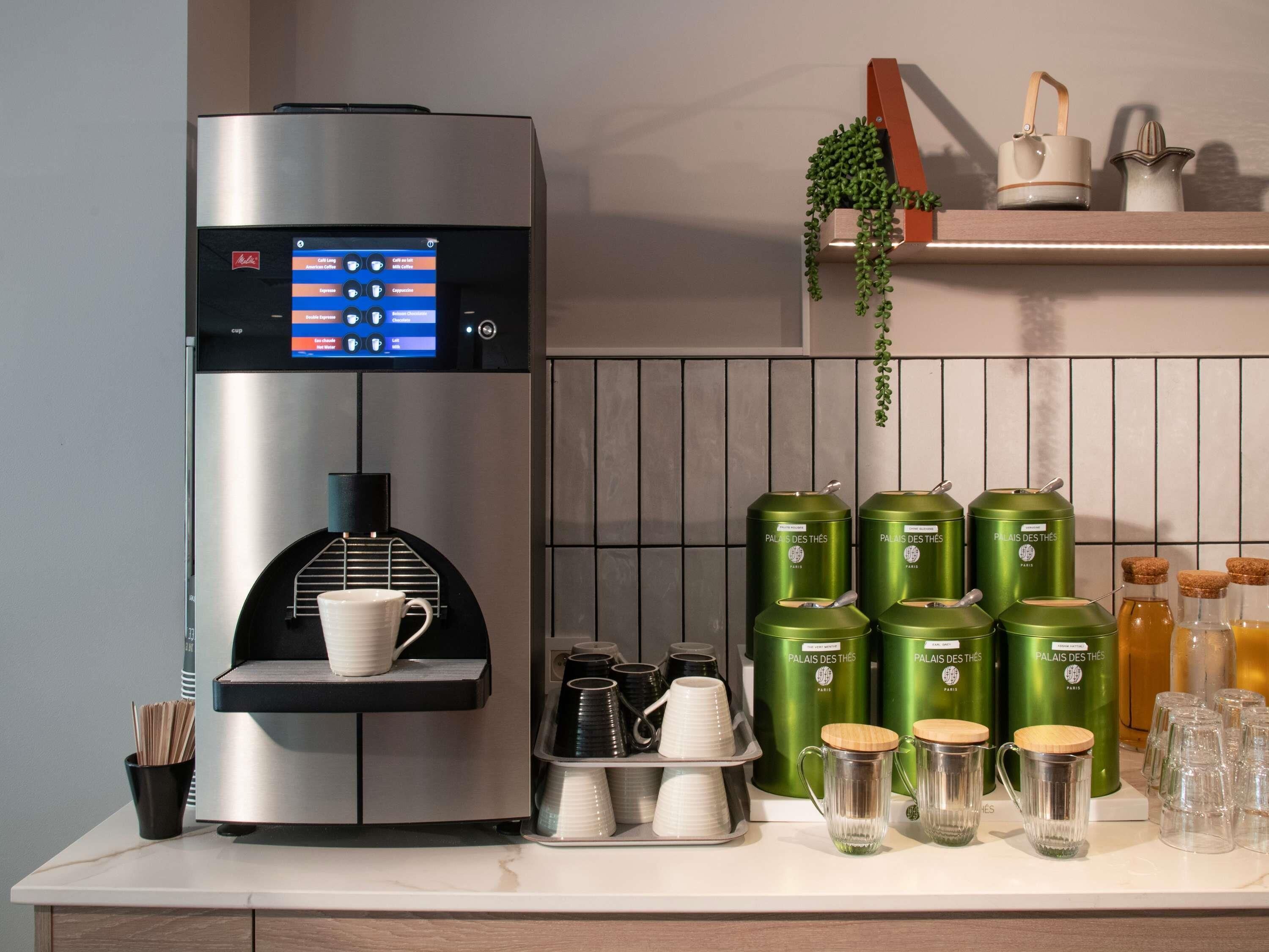 Una macchina per il caffè con display digitale, portacoppe e un vassoio con tazze e piattini.