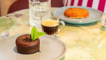 A dessert plate with a chocolate cake, a glass of coffee, and a plate with a pastry.
