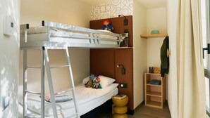 A bunk bed with a ladder, a small shelf with books, and a wooden ladder shelf. - ibis Sarlat (Sarlat-la-Canéda)