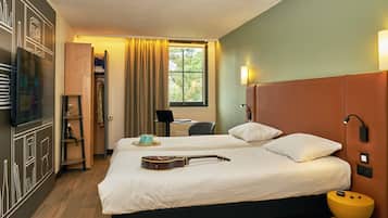 Habitación de hotel con cama, una guitarra, una laptop y un escritorio con silla.
