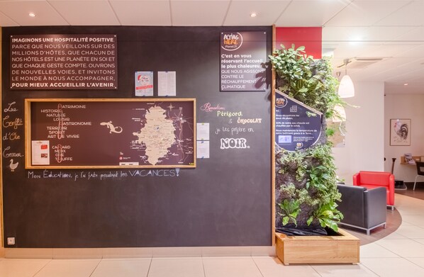 A hotel reception area with a blackboard displaying various information, including a map and a list of amenities. - ibis Sarlat (Sarlat-la-Canéda)