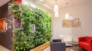 A modern interior with a vertical garden wall, seating area, and a map on the wall. - ibis Sarlat (Sarlat-la-Canéda)