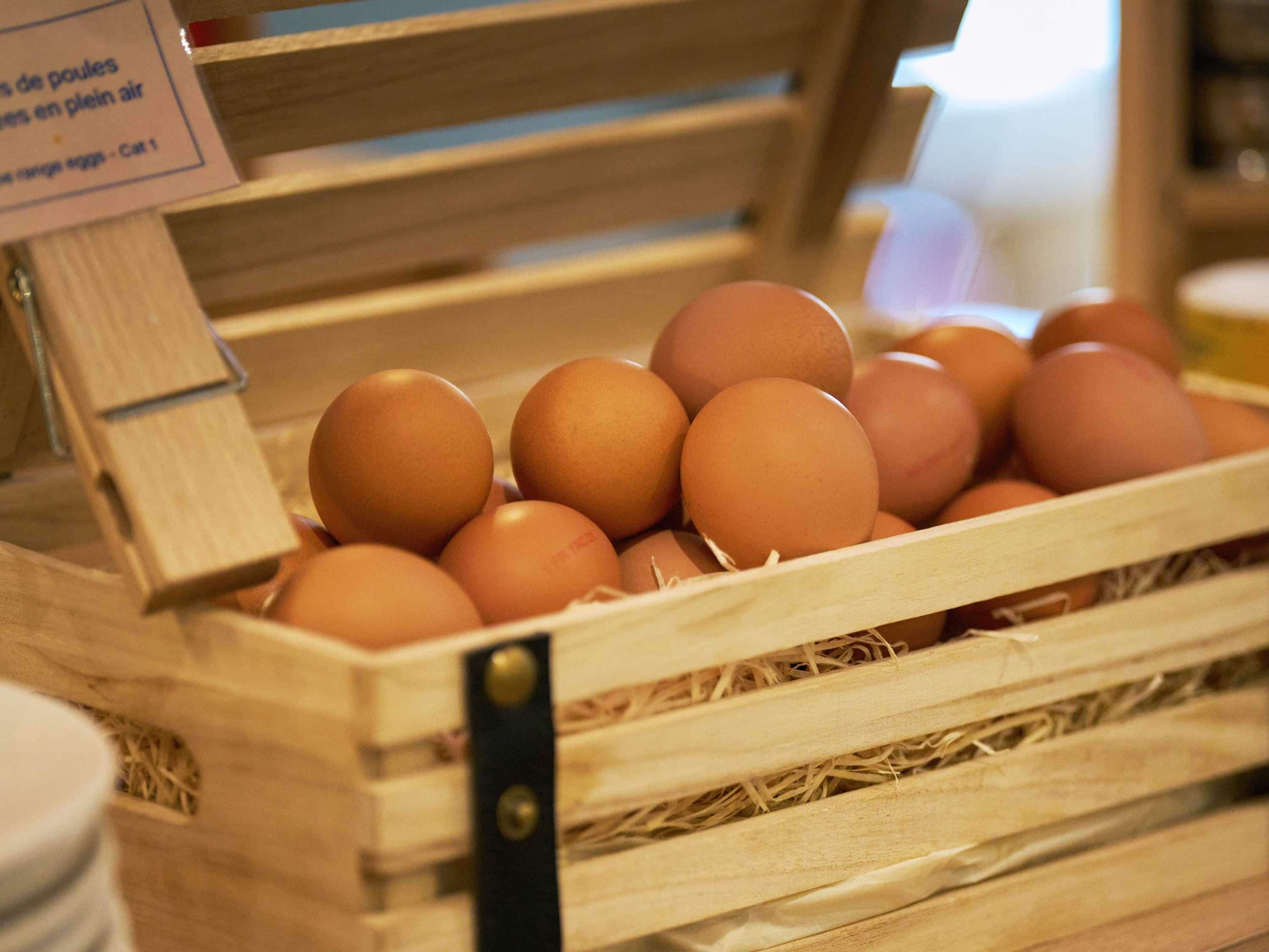 Una caja de madera llena de huevos marrones.