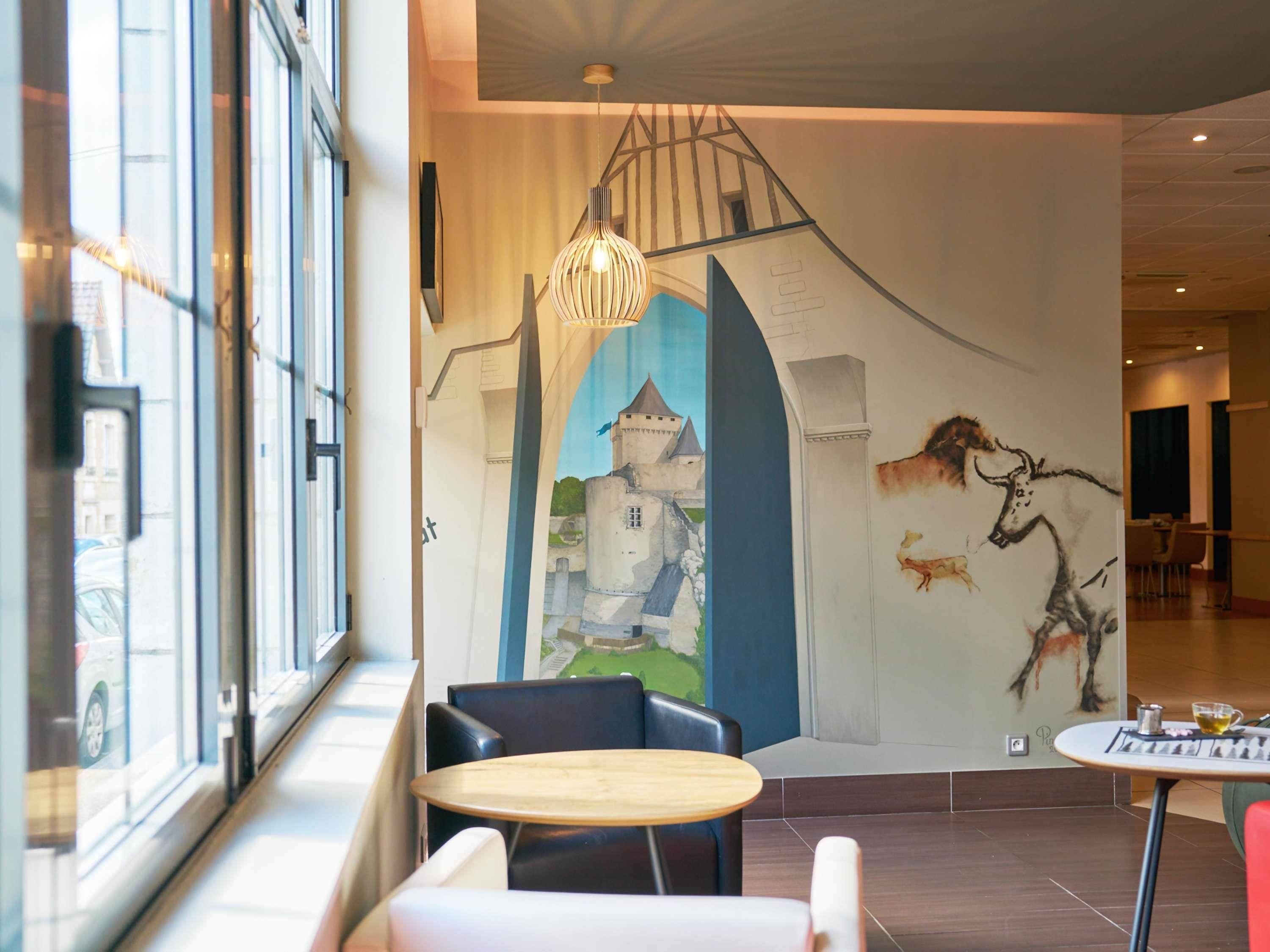 Un interior moderno con un mural, una mesa de madera y sillas de cuero negro.