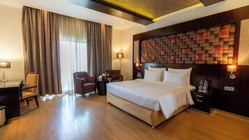 A hotel room with a large bed, a desk, a chair, a nightstand, and a wall with a geometric pattern.