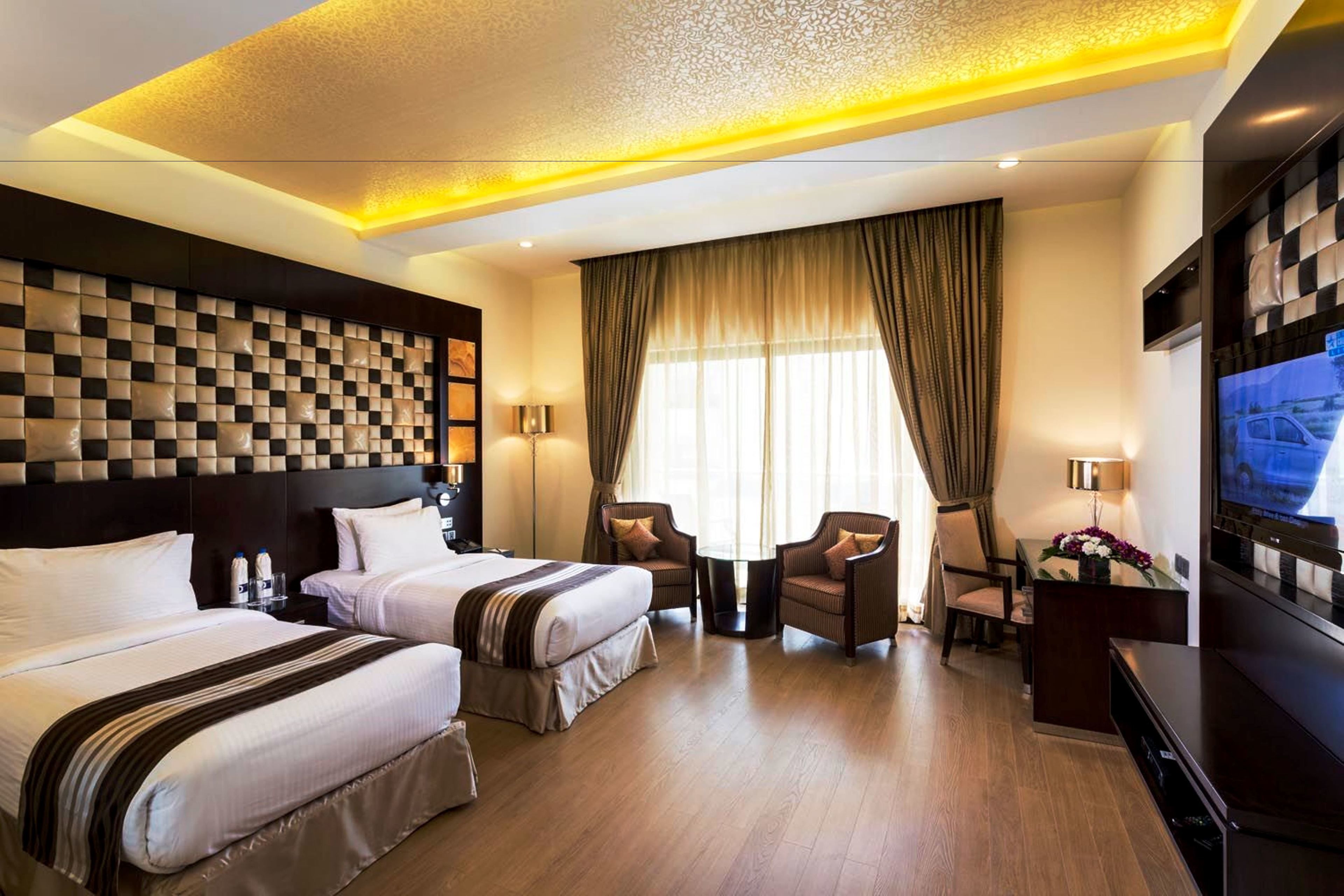 A hotel room with two beds, a TV, a desk, and a chair.