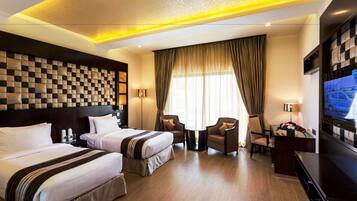 A hotel room with two beds, a TV, a desk, and a chair.