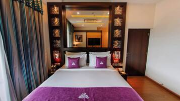 A hotel room with a bed, a nightstand, a mirror, and a door.