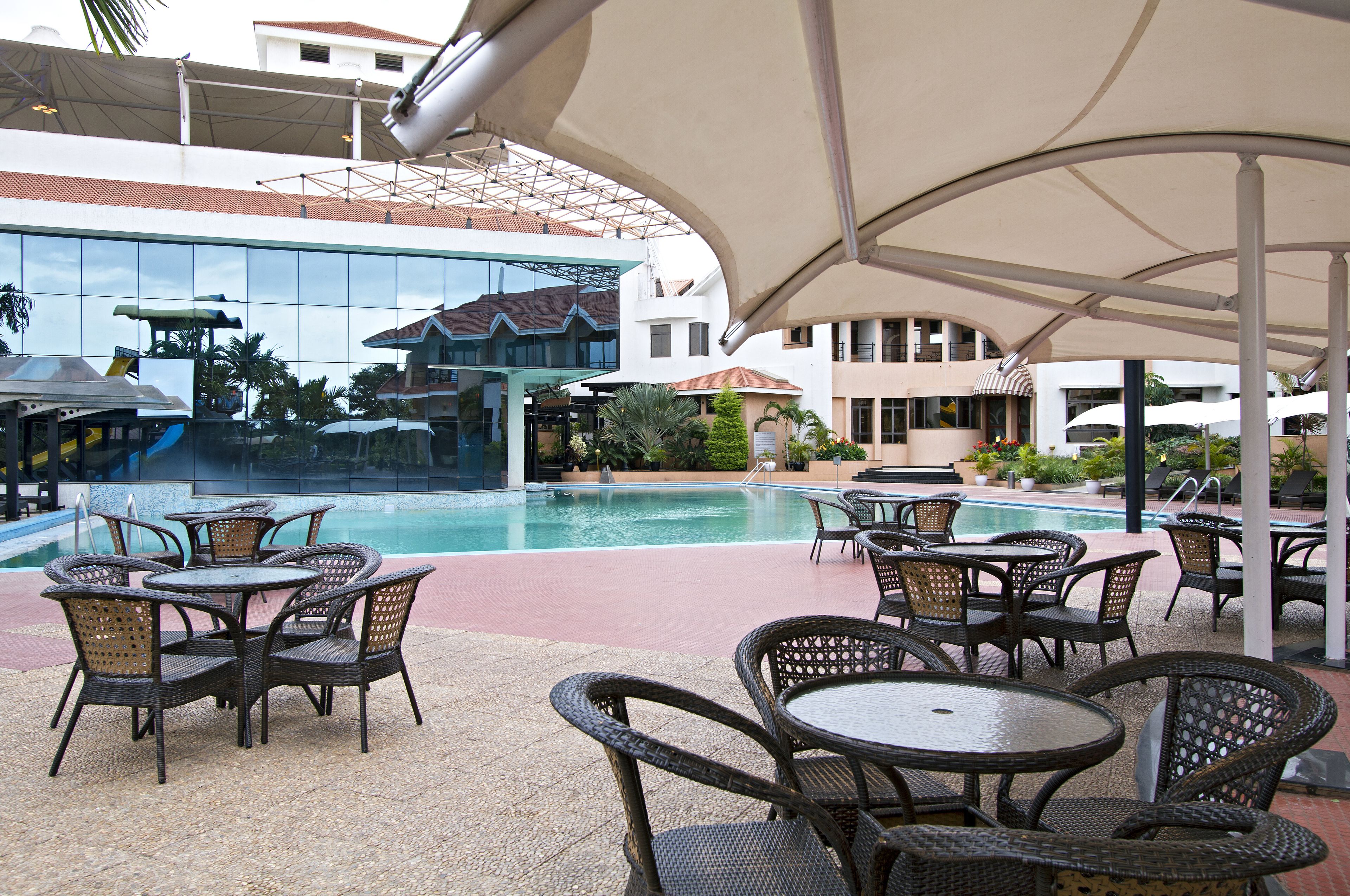 A poolside area with outdoor seating and a view of a building with a modern design.