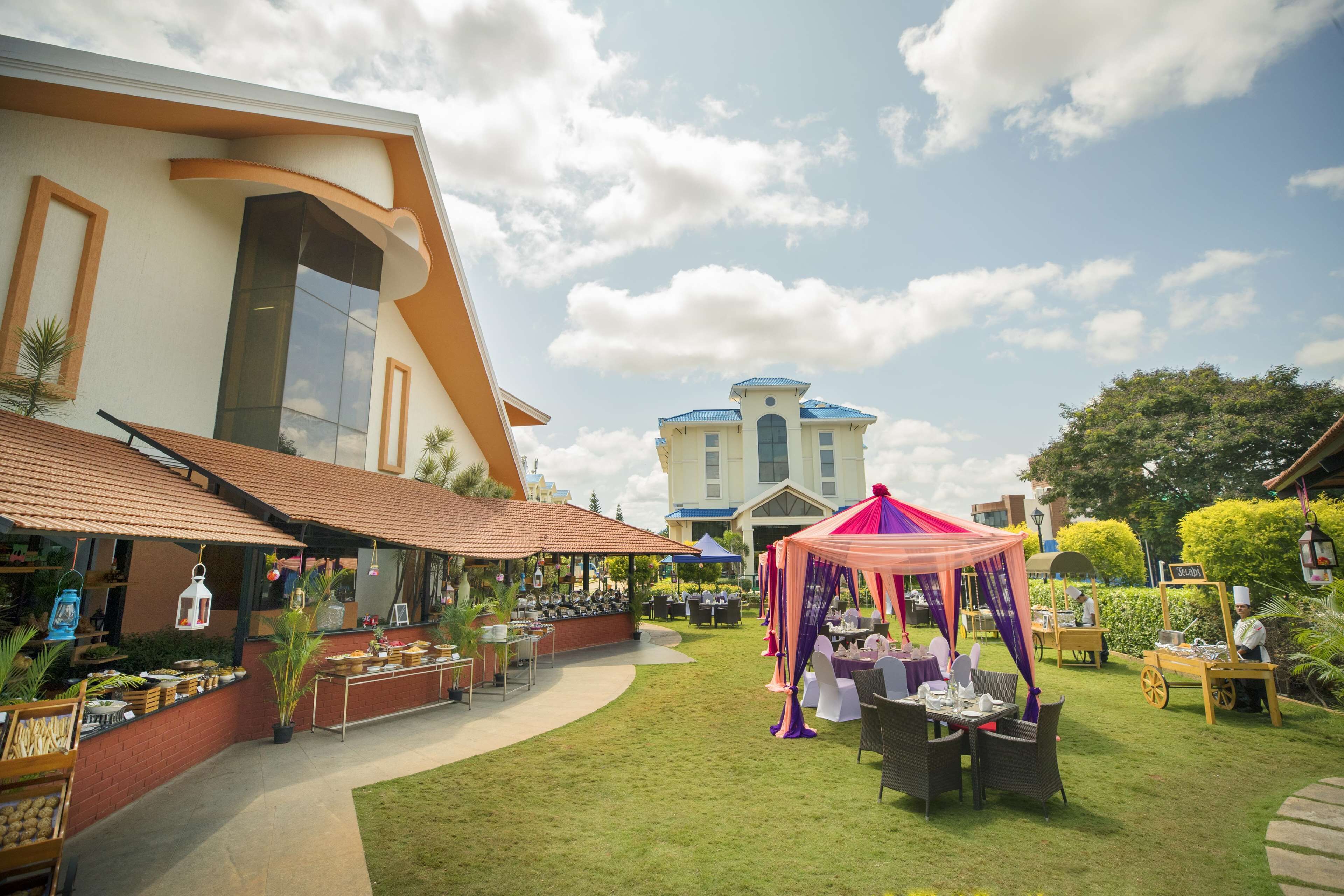 An outdoor dining area with tables and chairs, a food cart, and a tent.