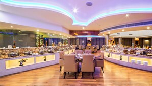 A modern restaurant with a central dining area and multiple buffet stations. - Aldovia Resort & Convention (Bengaluru)