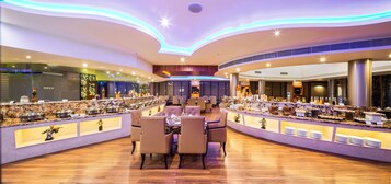 Um restaurante moderno com área de refeições central e várias estações de buffet.