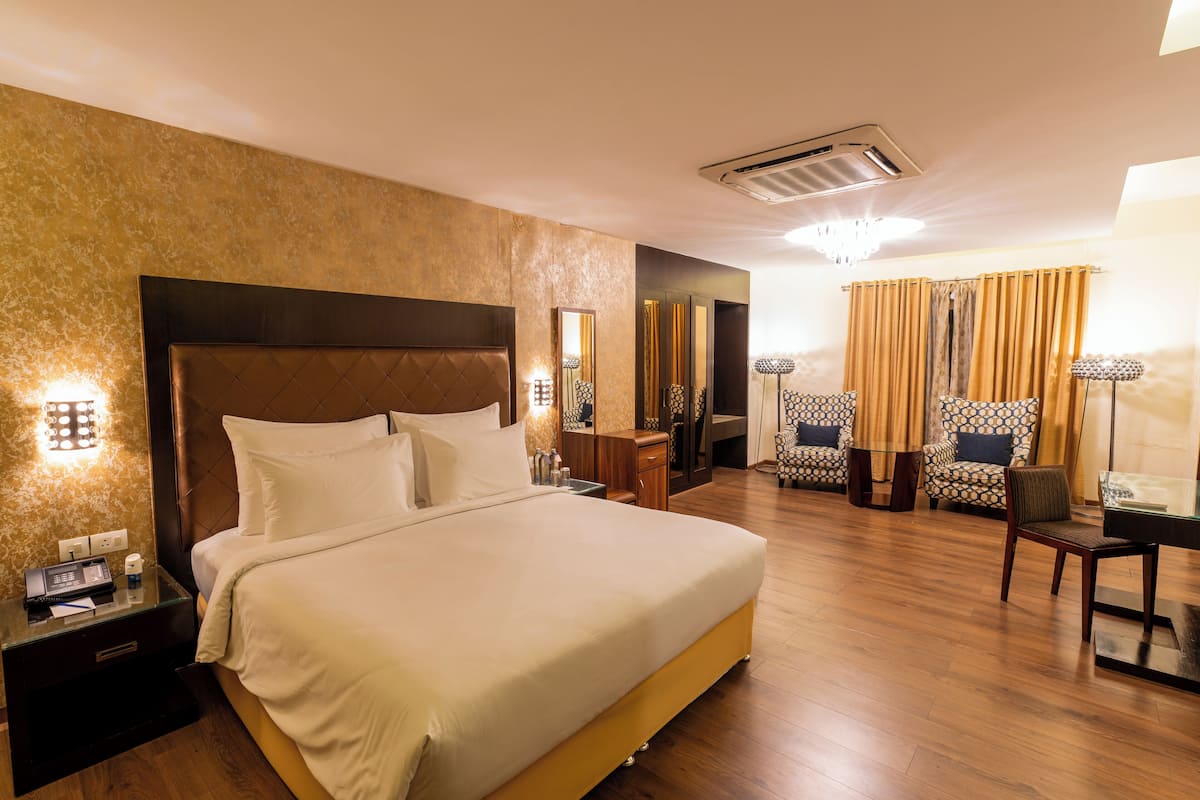 A hotel room with a large bed, bedside tables, a desk, a chair, and a mirror.