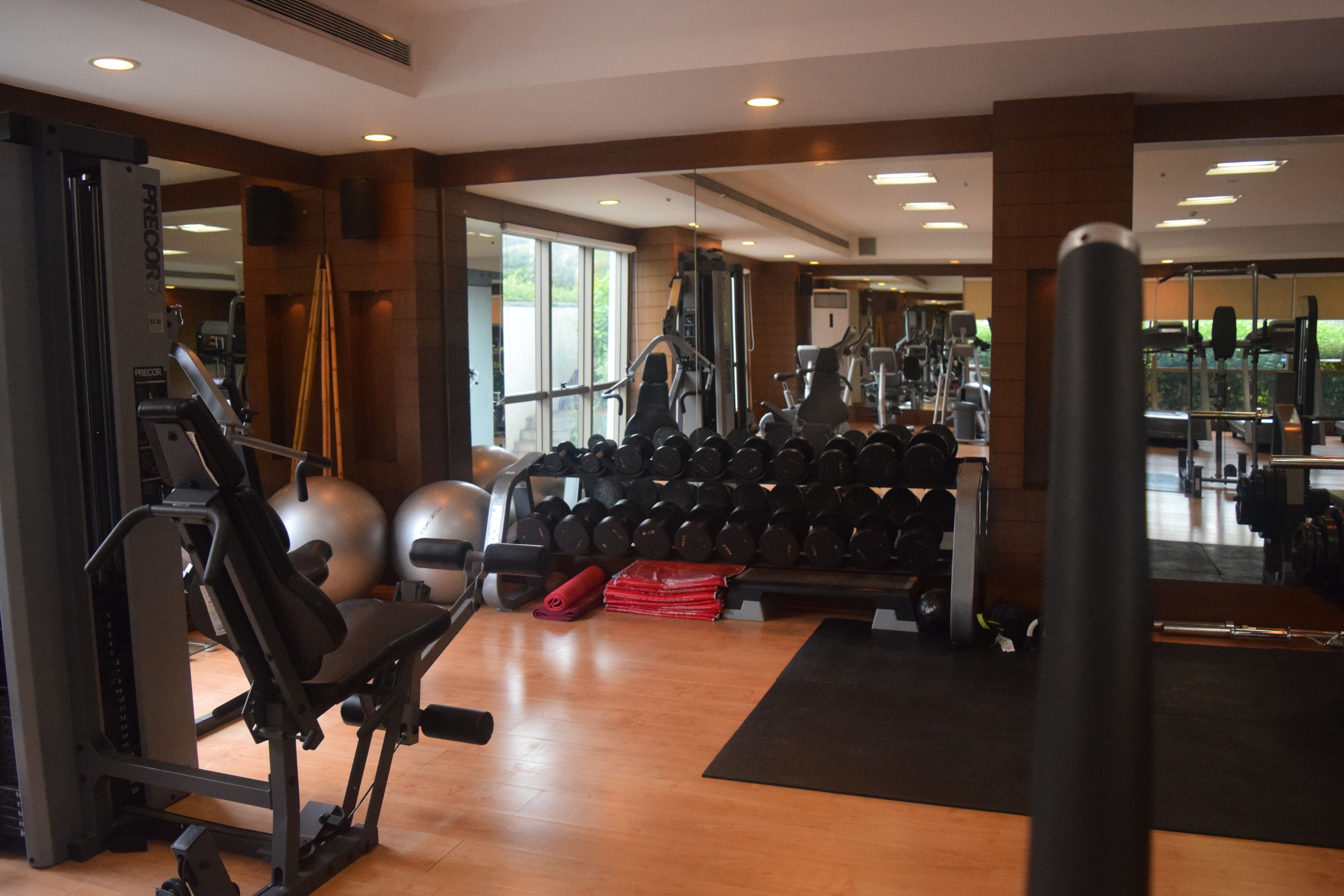 Uma academia com equipamentos de exercícios, pesos e espelho.