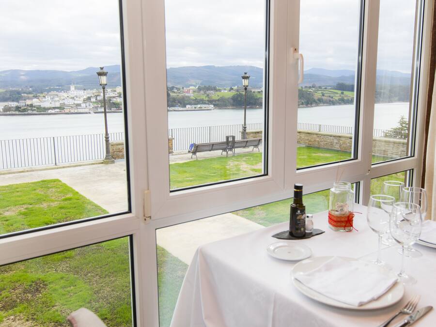 Mesa posta para refeição, com vista para um rio e colinas ao longe.