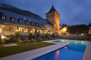 A hotel with a swimming pool, lounge chairs, and a tower. - Parador de Arties (Naut Aran)