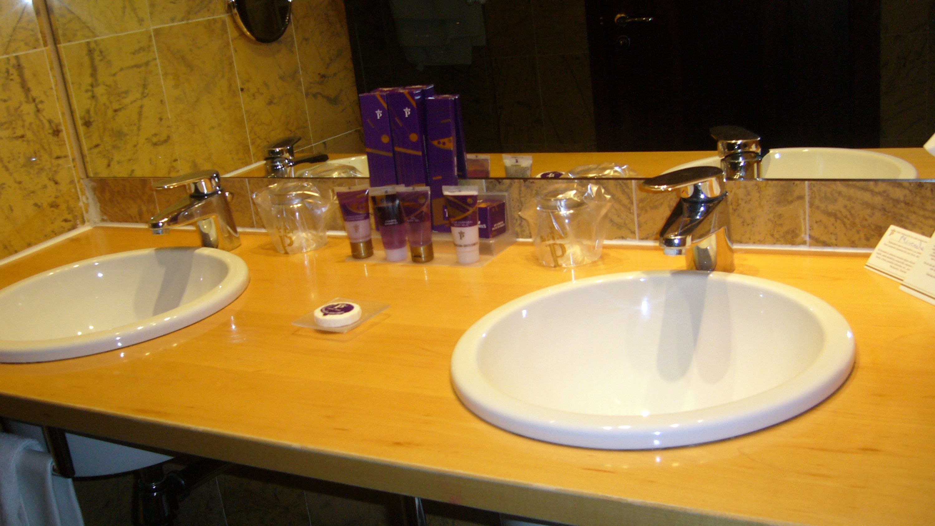 A bathroom with two sinks, a mirror, and toiletries on the counter.