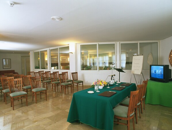 A conference room with a long table, chairs, a projector, and a television screen. - Parador De Melilla (Melilla)