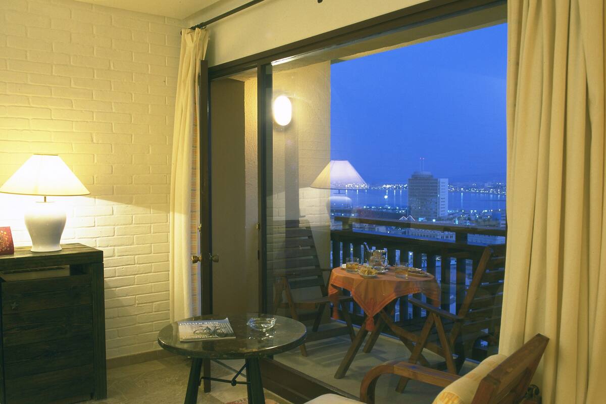 Un balcon avec une table, des chaises et une lampe.