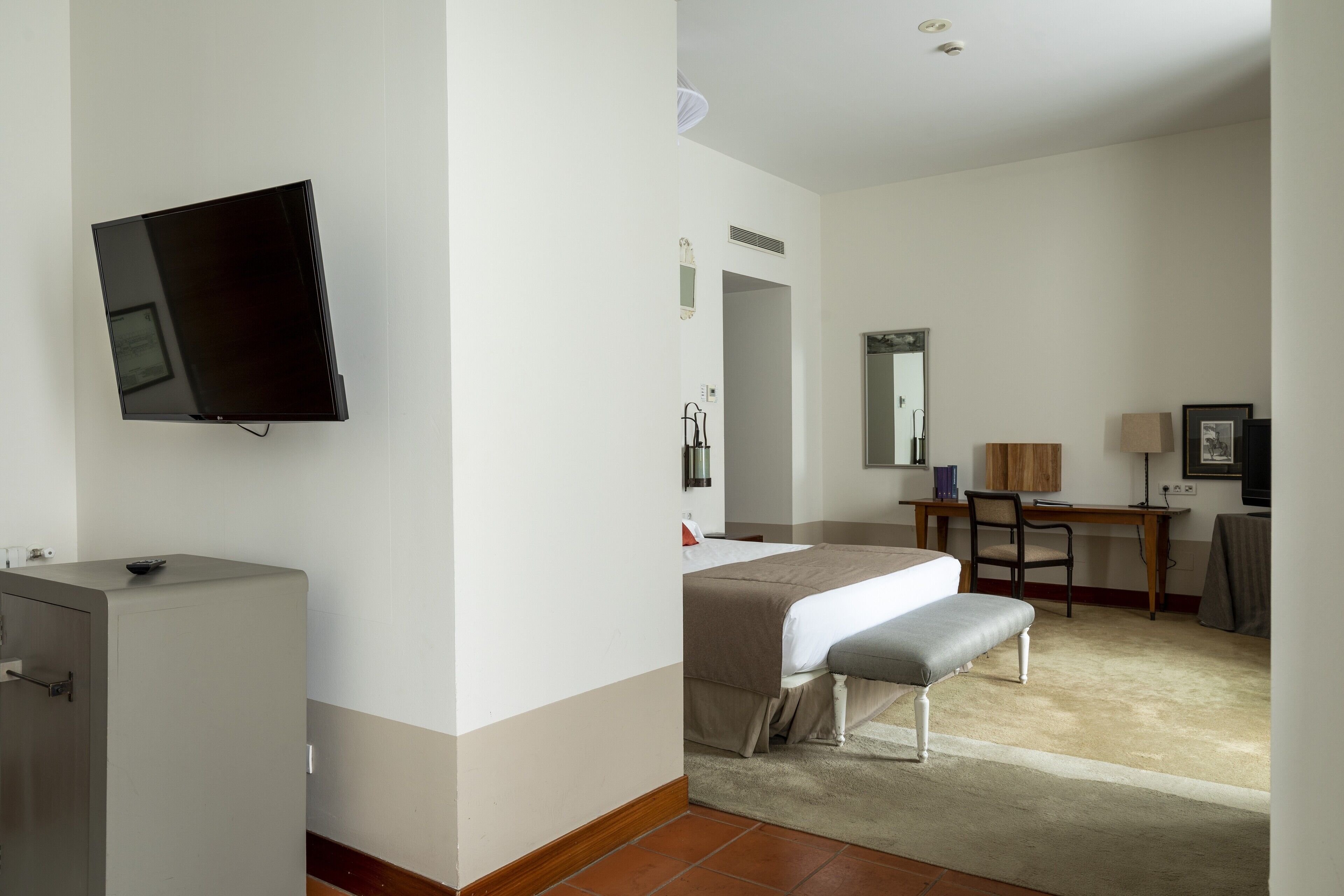 Une chambre d’hôtel équipée d’un lit, d’un bureau, d’une chaise, d’une télévision et d’un mini-bar.