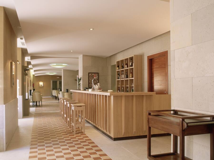 Un hall de hotel con mostrador de recepción, zona de estar y un escritorio de atención al cliente.