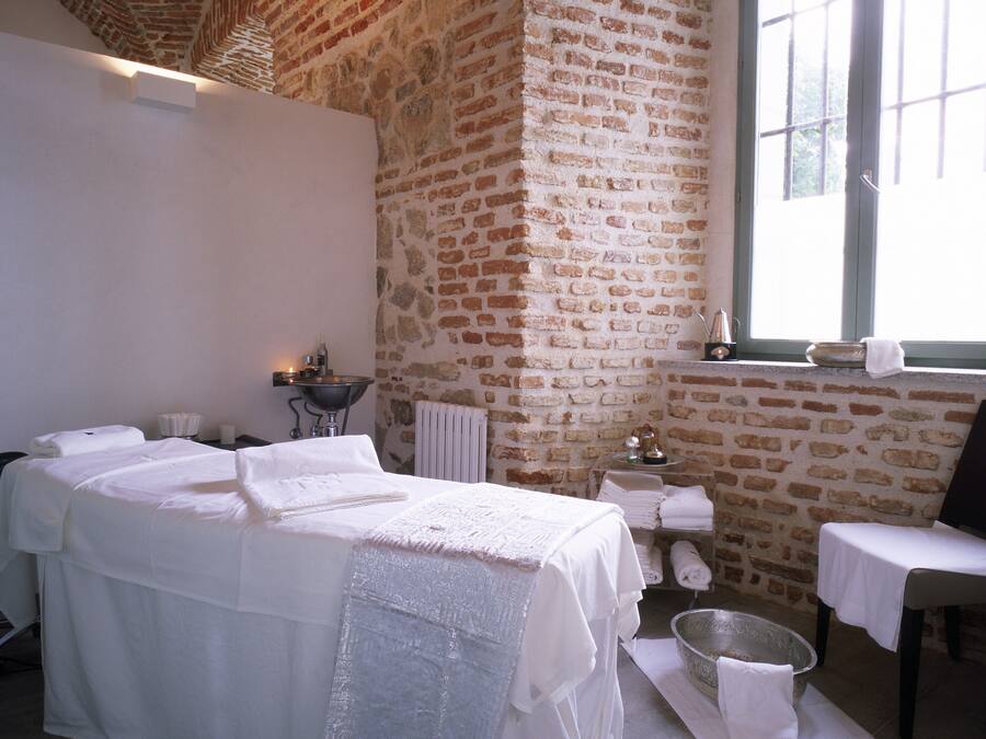 A room with a large bed, a small table with a bowl and towels, and a window with a view.