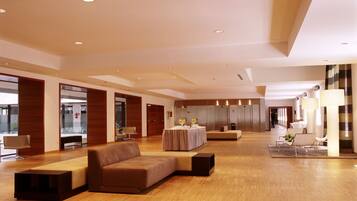 A spacious lobby with a wooden floor, a brown sofa, and a round table with a white tablecloth.
