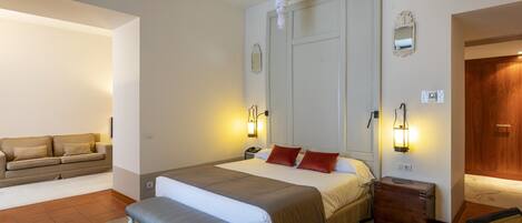 A bedroom with a bed, bedside tables, a bench, a wooden dresser, and a mirror on the wall.
