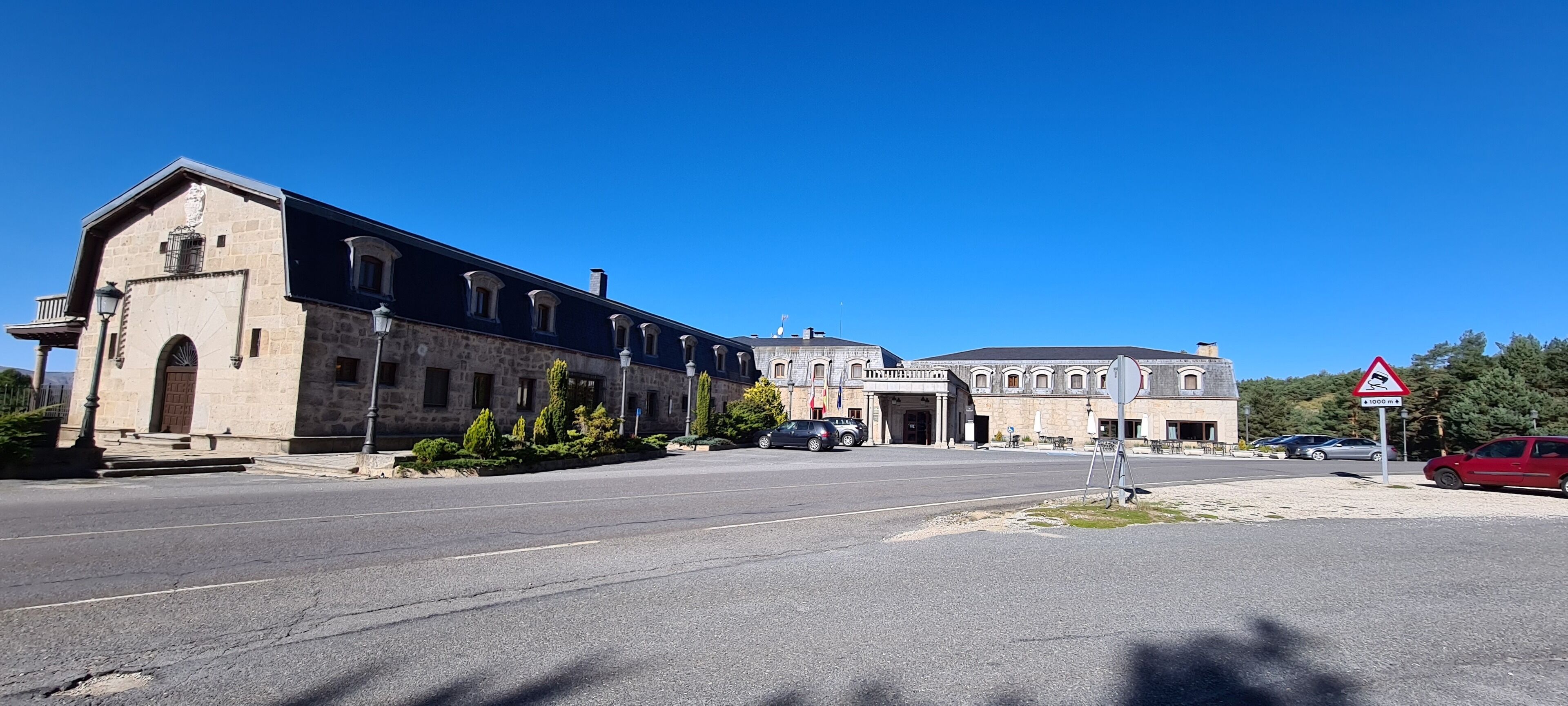 Un gran edificio de piedra con una entrada central, varias ventanas y un asta de bandera.