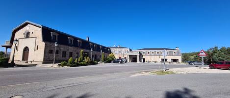 Un gran edificio de piedra con una entrada central, varias ventanas y un asta de bandera.