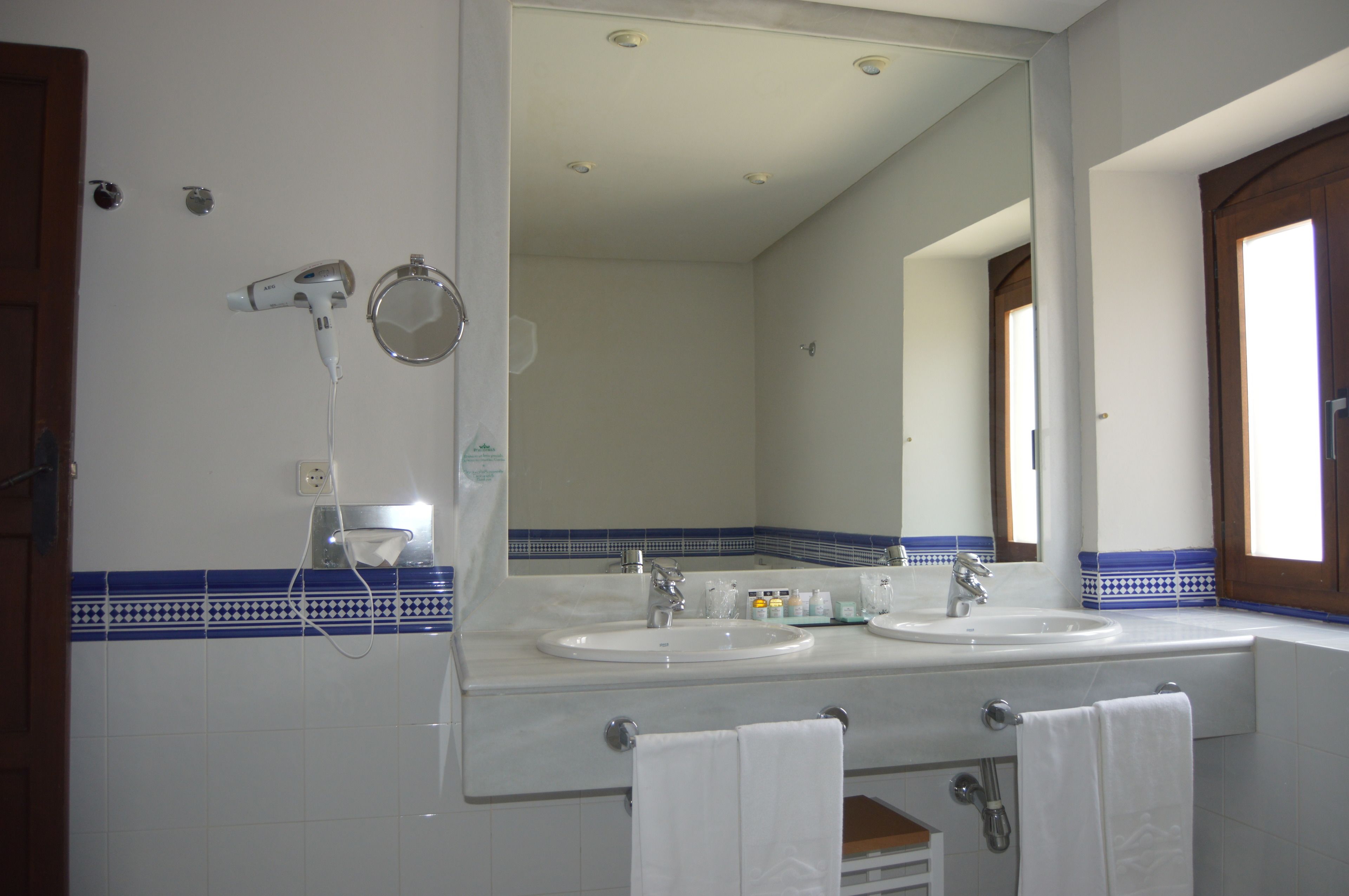 A bathroom with two sinks, a hairdryer, and a mirror.