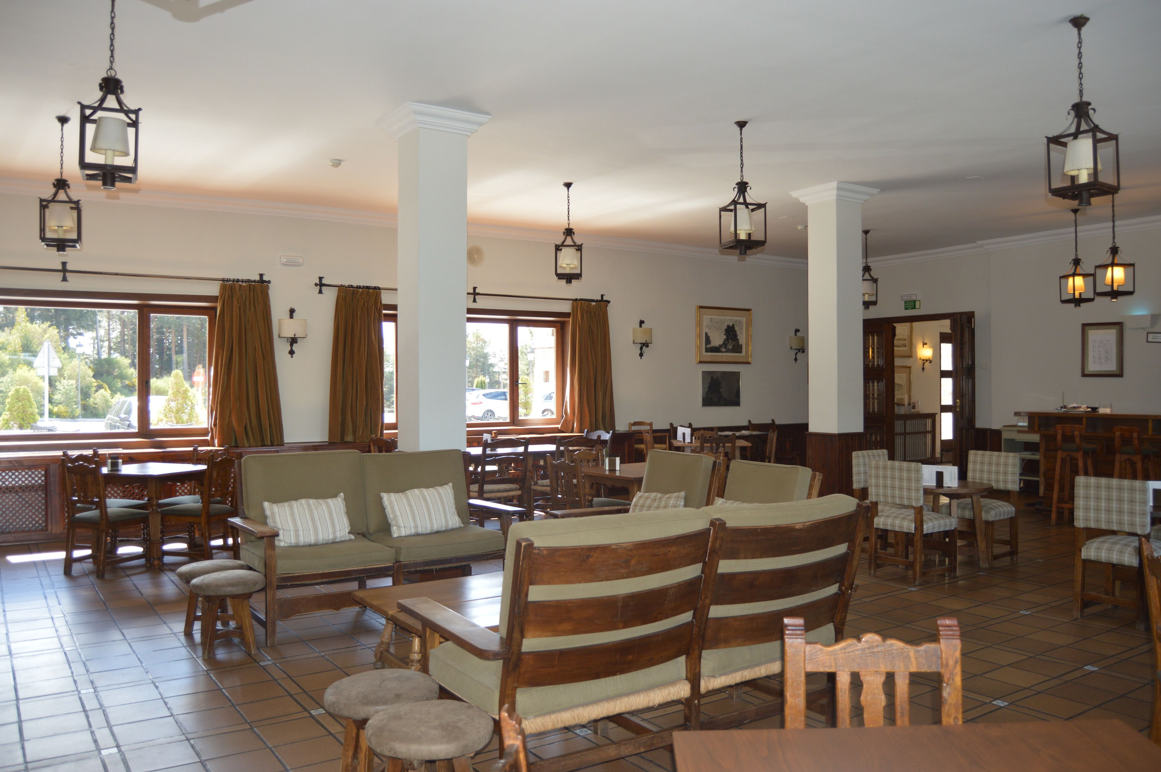 A spacious dining area with wooden furniture, hanging lanterns, and large windows offering a view of the outdoors.