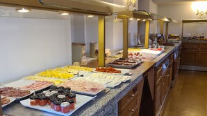 A buffet with various food items including meats, cheeses, and fruits.