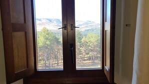 A wooden door leading to a view of a forested area with hills in the background.
